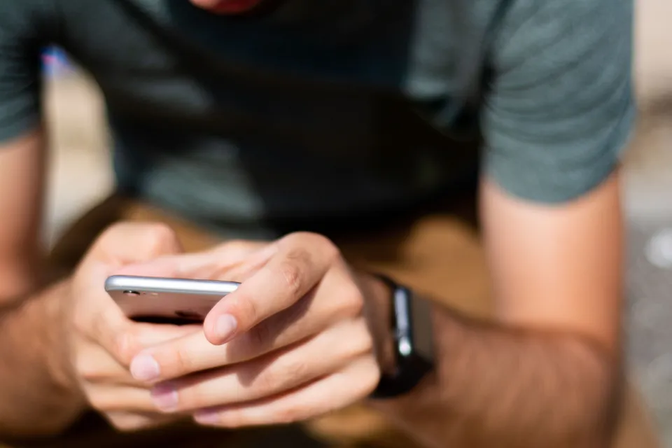 Close-up of hands using smartphone outdoors, depicting modern mobile communication.