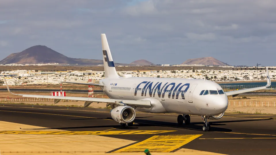 Finnair aircraft on runway with Lanzarote's volcanic landscape in background.