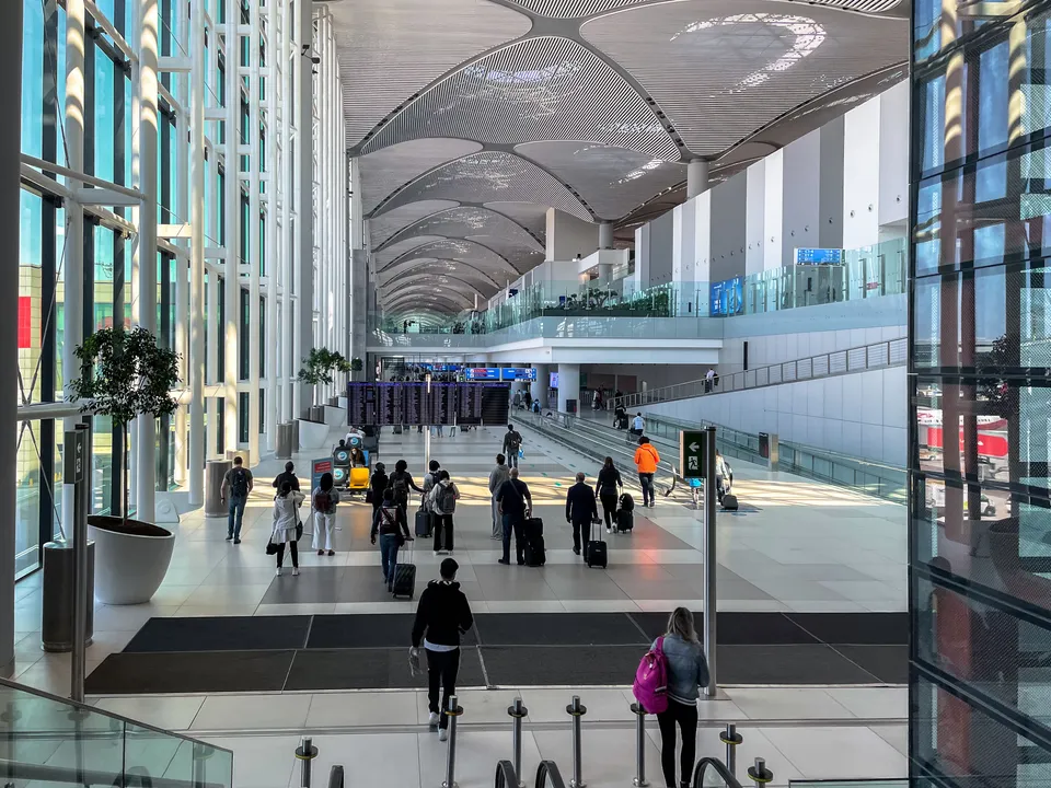 Travelers walking through the spacious modern terminal at Istanbul Airport.