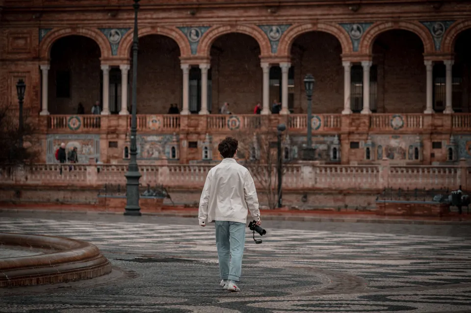 A person with a camera explores the historic Plaza de España in Sevilla, Spain.