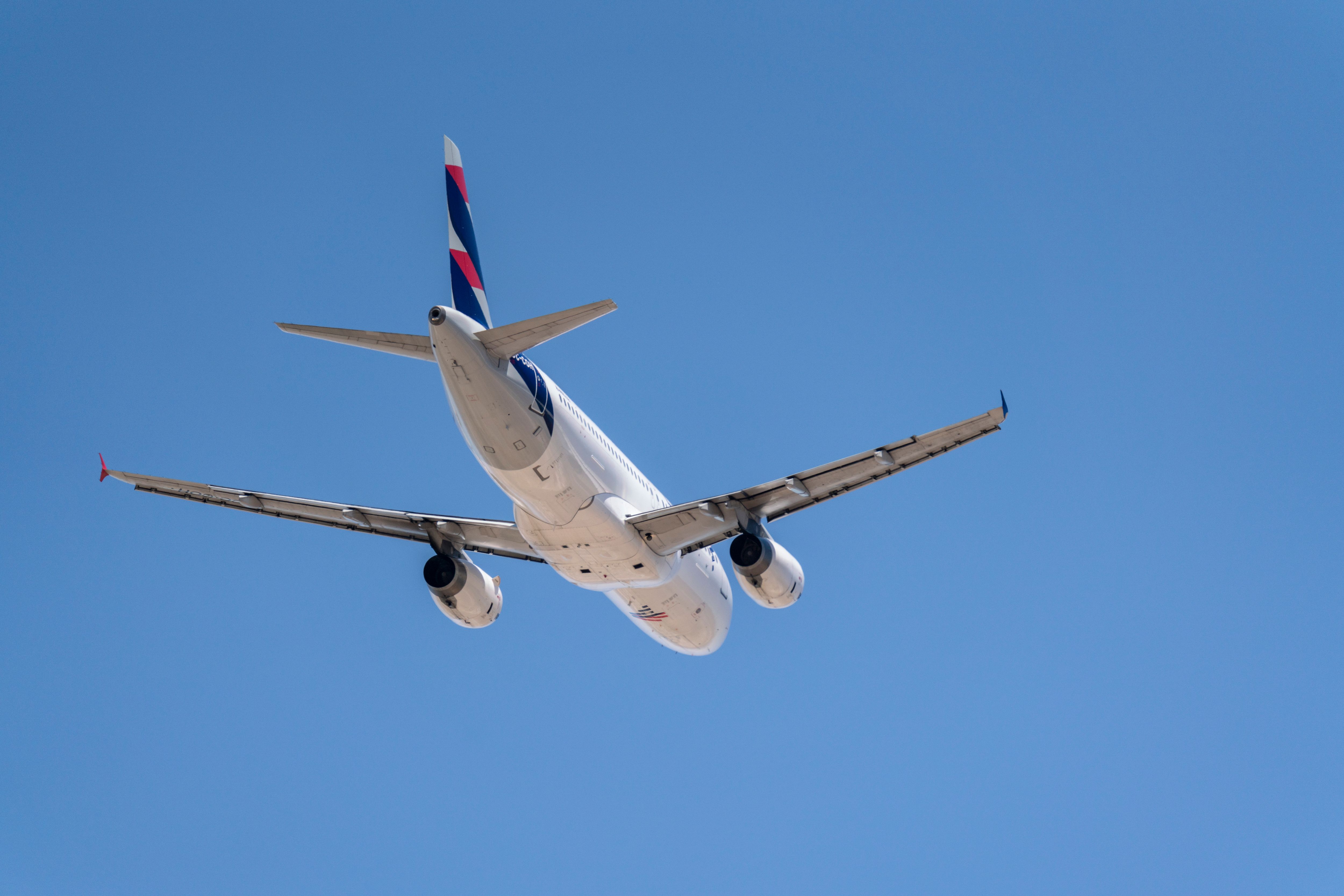 A commercial airplane ascends against a clear blue sky in Santiago, Chile.