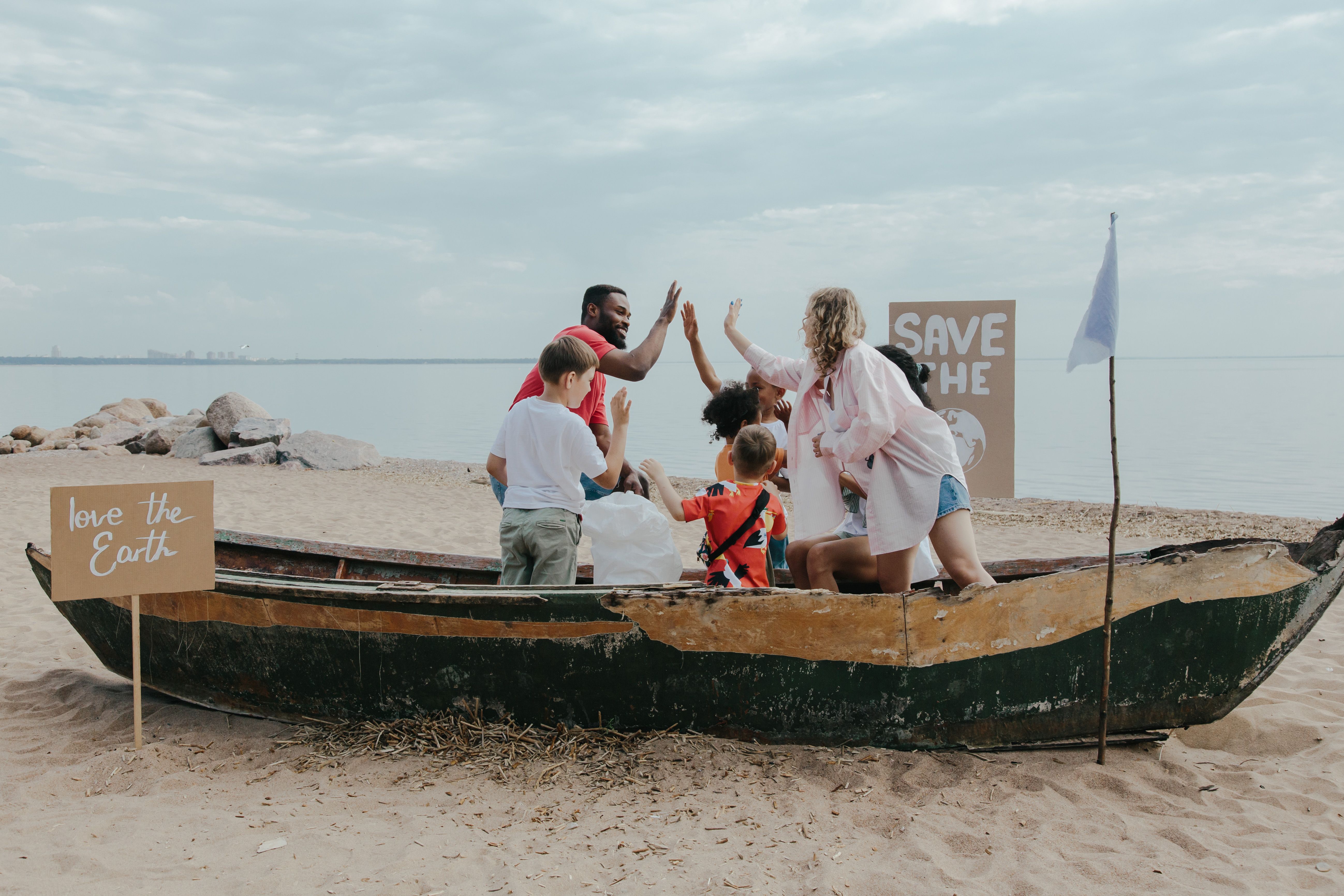 A diverse group of volunteers celebrates teamwork during a beach cleanup.