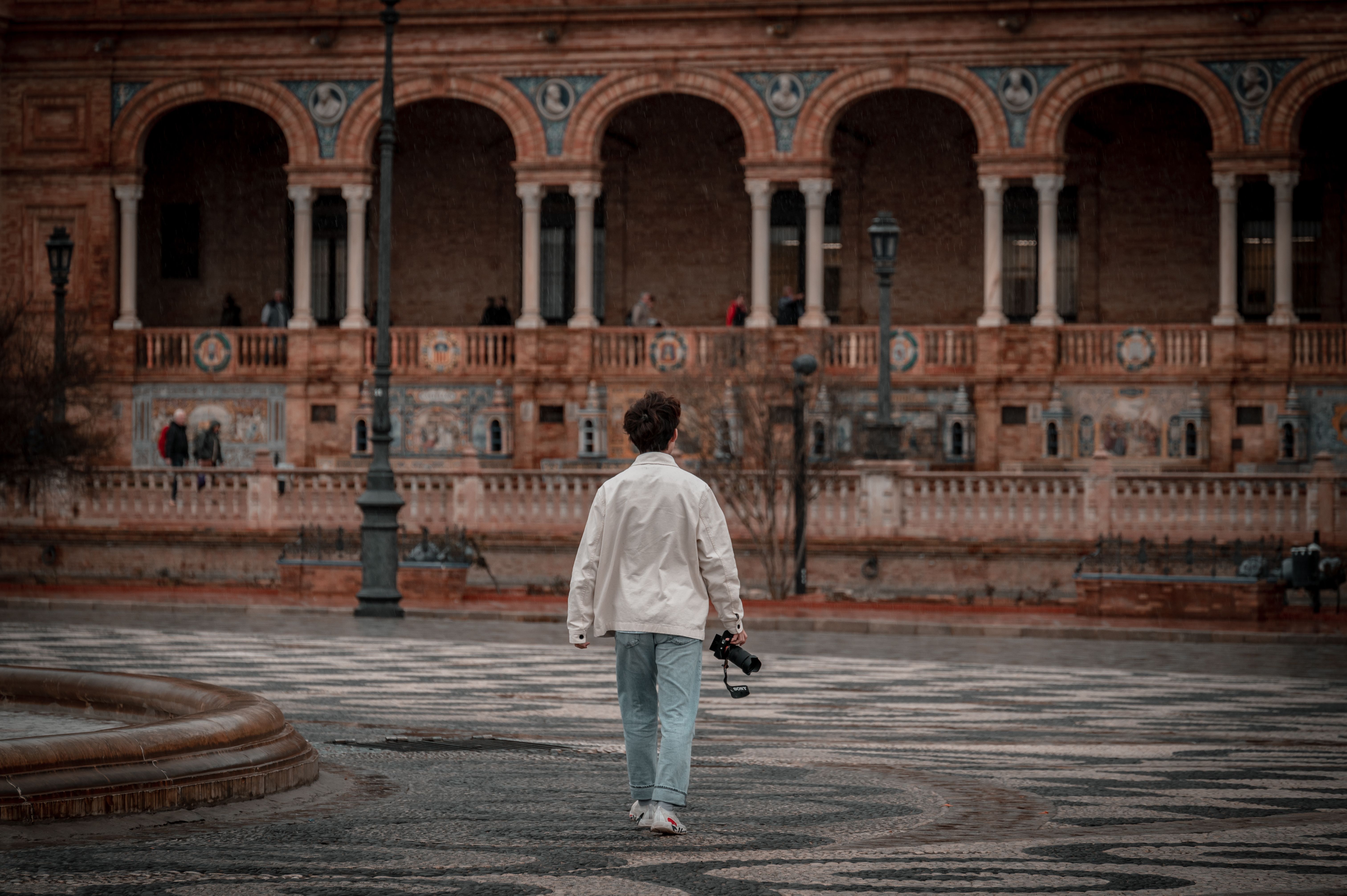 A person with a camera explores the historic Plaza de España in Sevilla, Spain.